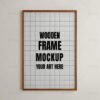 A wooden frame mockup with a blank interior mounted on a light beige wall.