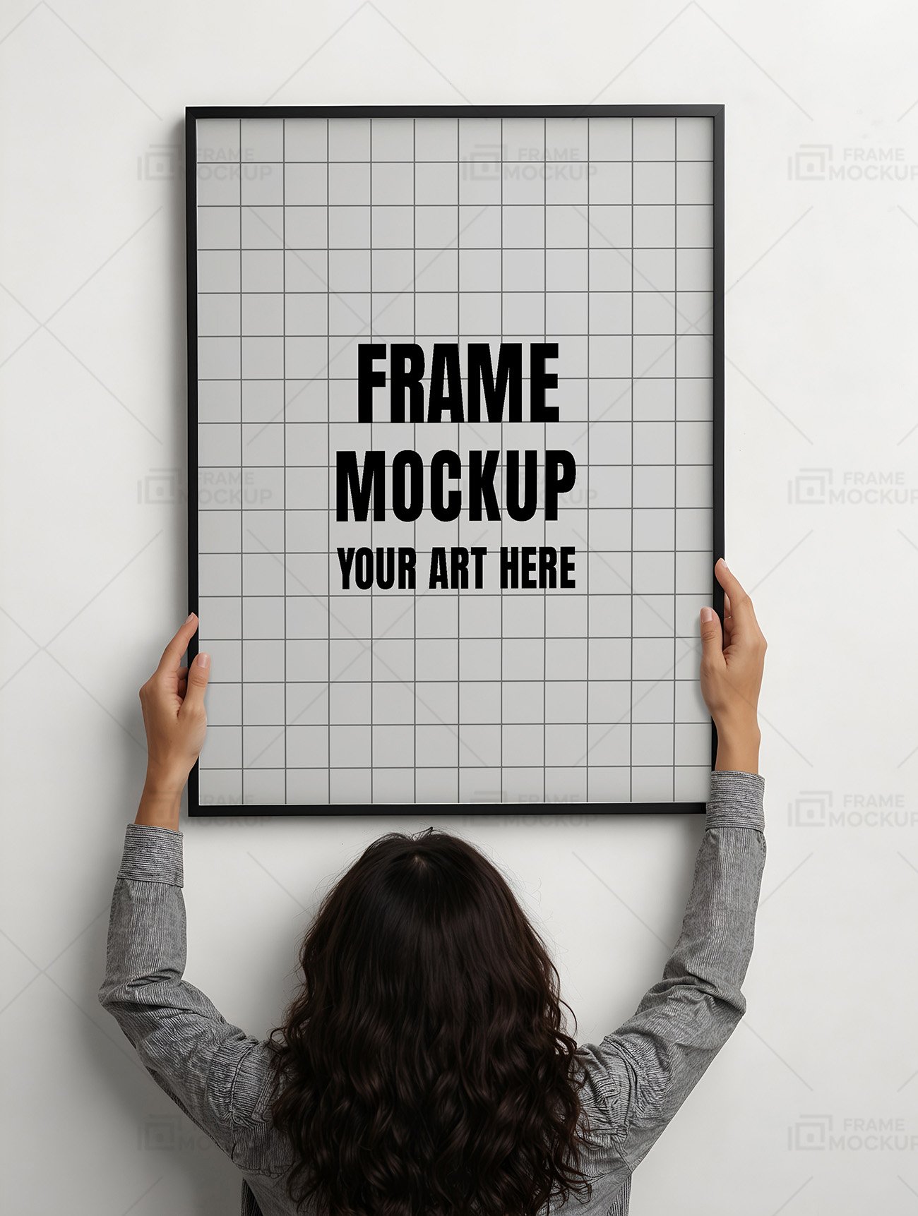 Frame mockup PSD featuring a person holding a large black-framed empty in front of a white wall.