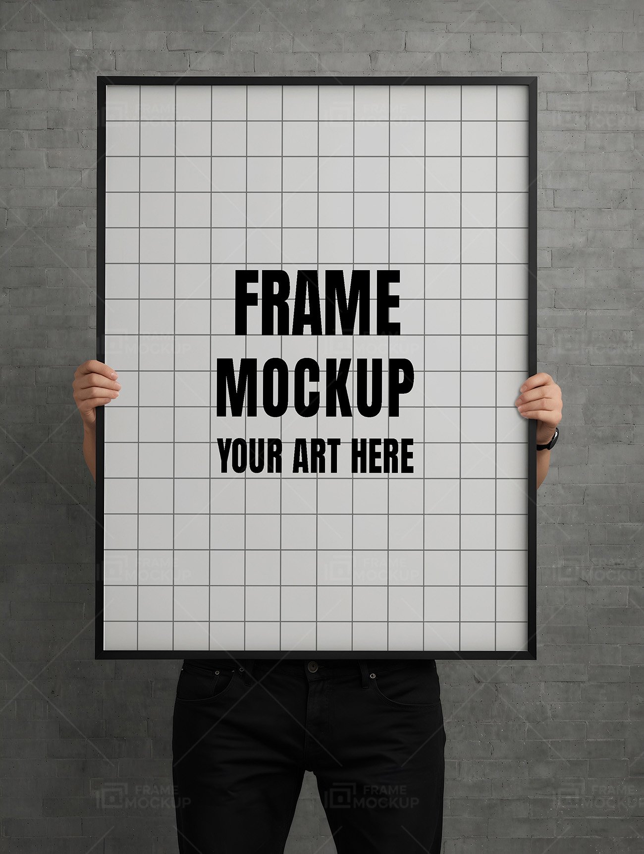 Frame mockup PSD featuring a person holding a large black-framed empty canvas against a gray brick wall.