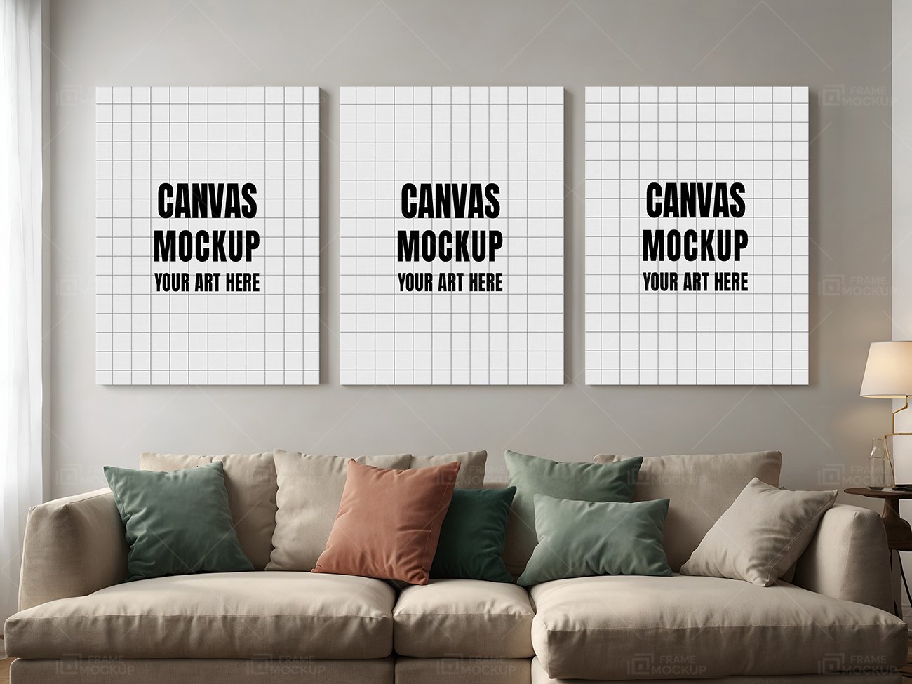 Three blank canvas mockups on a wall above a cozy sofa with colorful cushions, illuminated by natural light.